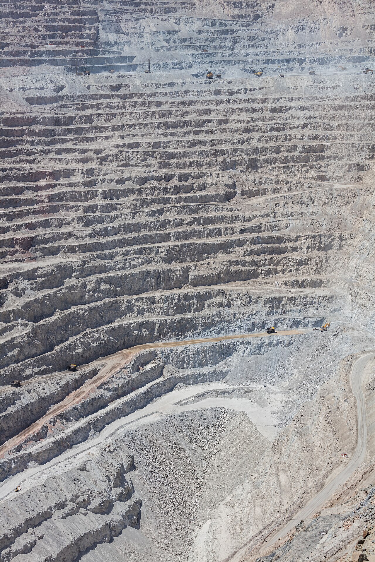 Open-pit quarry with rock benches and haul trucks, industry scene